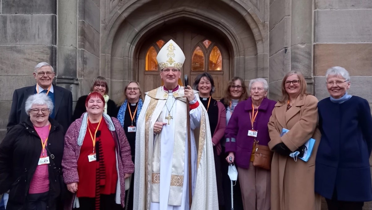 Bishop Mark Davies with a group of people outside All Saints Church, Stand